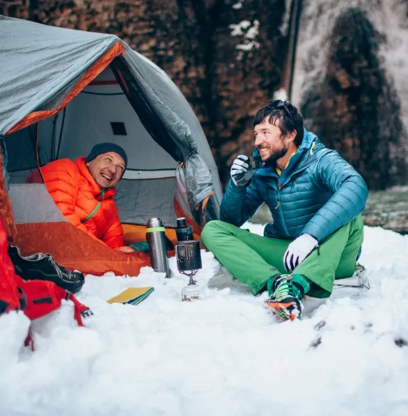 Climbers in insulated clothing at their tent on a snowy mountain