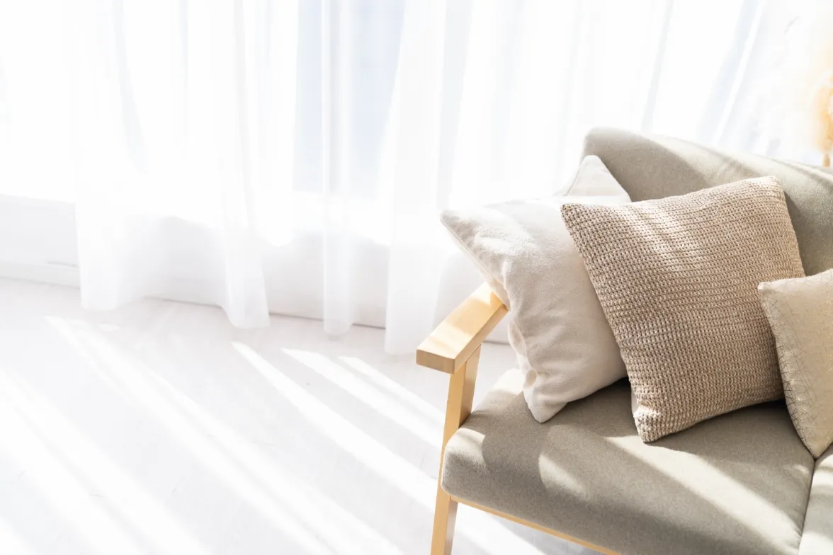 Sunlight coming through a lace curtain into a living room with a sofa