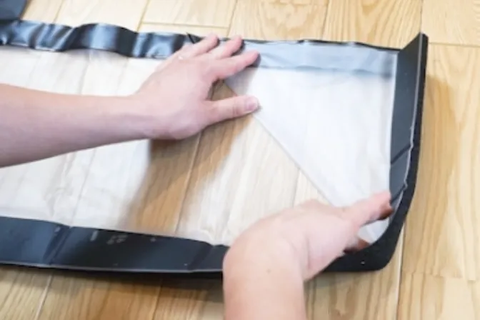 Pressing the triangular folded sheet flat to fit the entrance opening